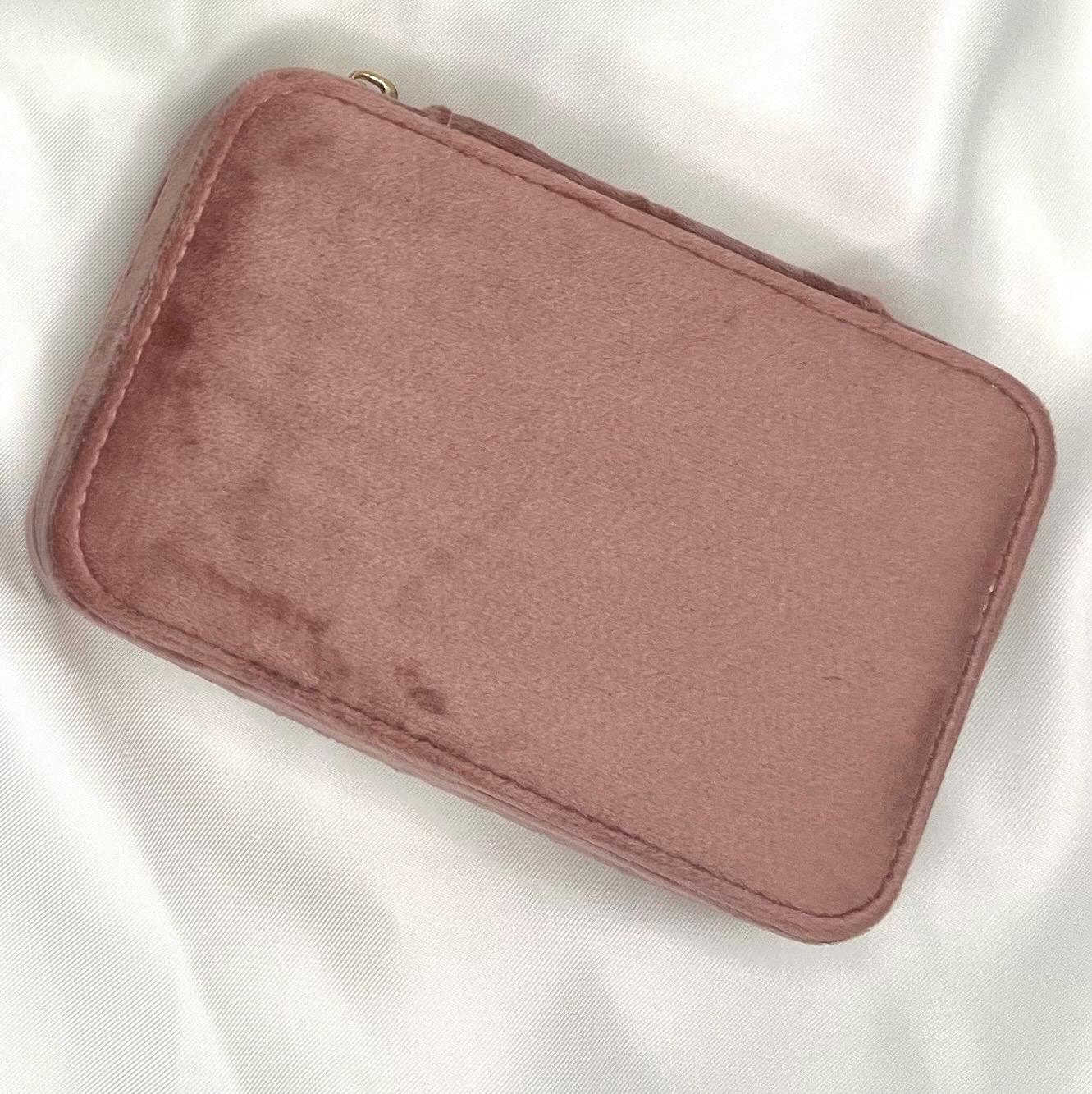 Sichere dir deine personalisierte Schmuckaufbewahrung aus 100 % recyceltem Polyester-Samtgewebe. Erhältlich in den Farben Dark Emerald, Moonstone und Rose Quartz, kannst du dein Etui mit deinem Namen personalisieren. Das kompakte Etui (15 x 10 x 5,9 cm) bietet Platz für Ringe, Ohrringe und Halsketten, mit Fächern, Haken und Samtfutter zum Schutz vor Kratzern. Der Reißverschluss und die Schieber sind goldfarben. Ein stilvolles und nachhaltiges Accessoire für deine Schmuckaufbewahrung.